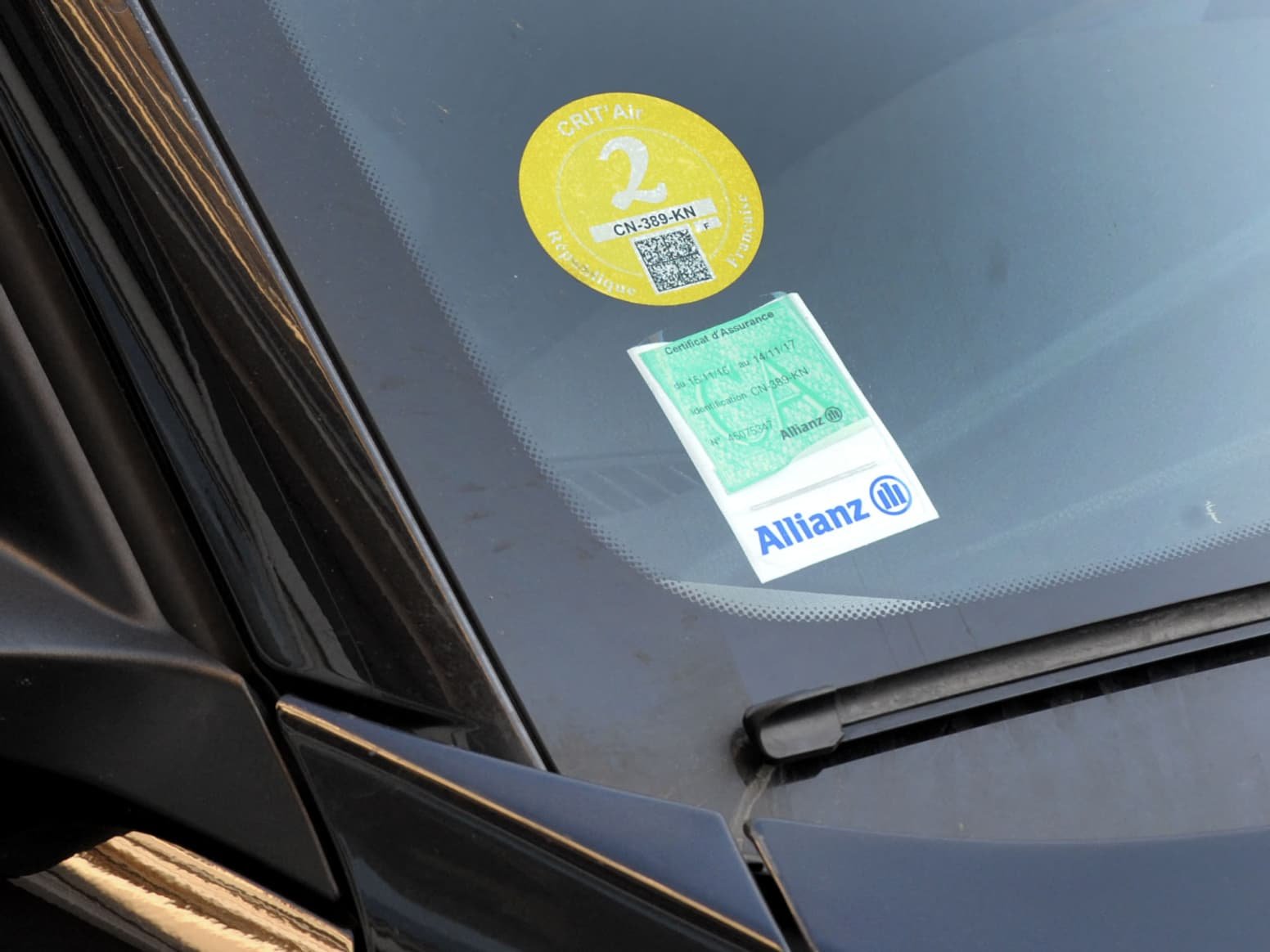 Certificat d’assurance et vignette Crit’Air collés sur un pare-brise